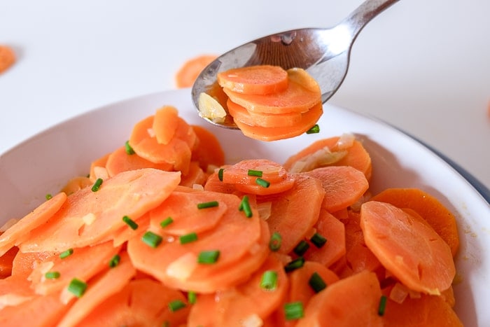 carrot salad in bowl with silver spoon lifting carrots away