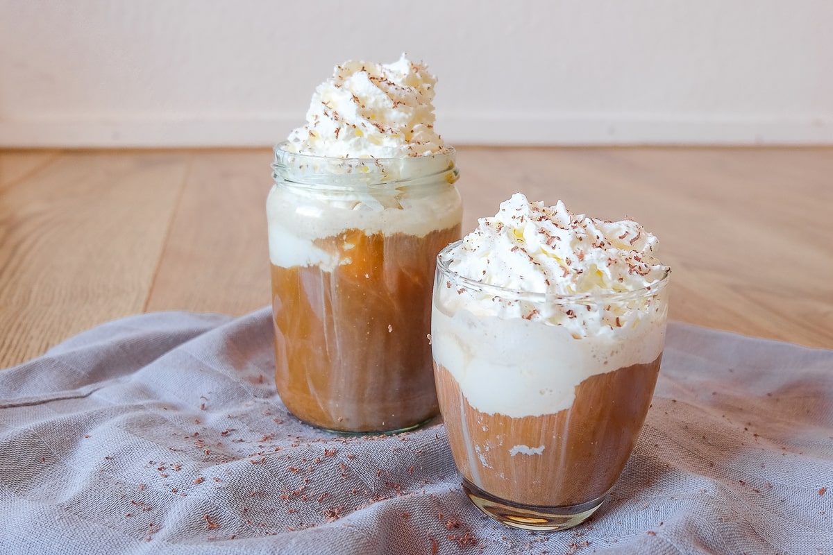 two glasses of ice cream coffee with whipping cream on wooden table