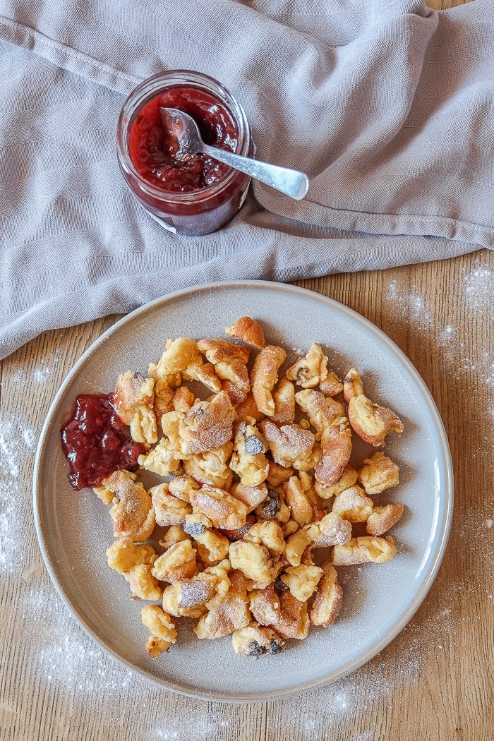 top view of grey plate with kaiserschmarrn pancake on it with jar of jam beside