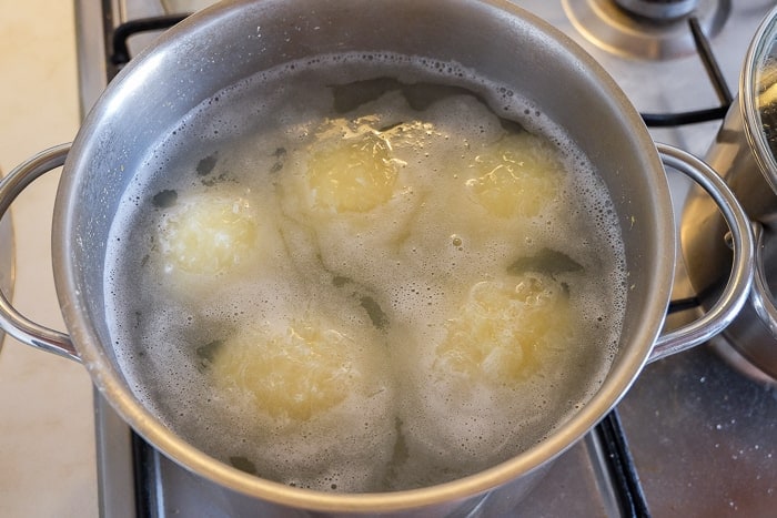 floating german potato dumplings in silver pot on stove