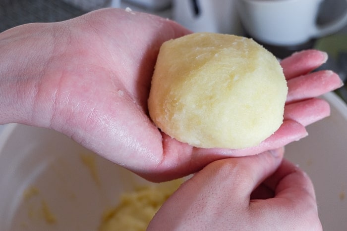 raw german potato dumpling formed into ball in hand