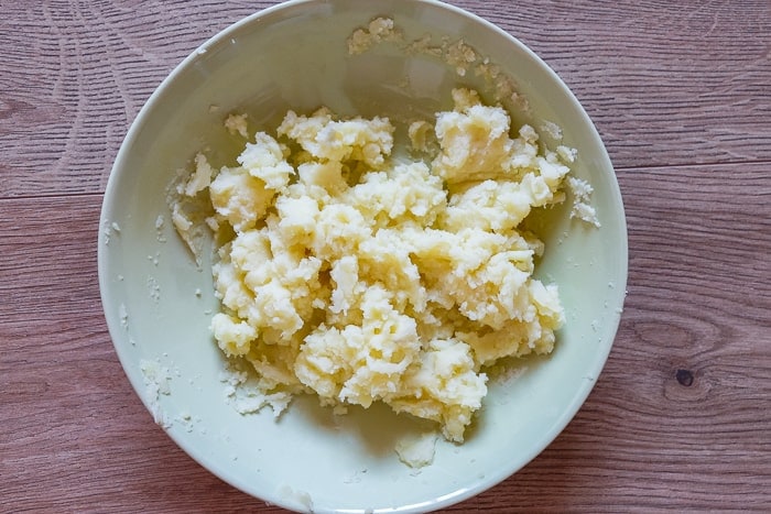 mashed potatoes in shallow bowl on wood