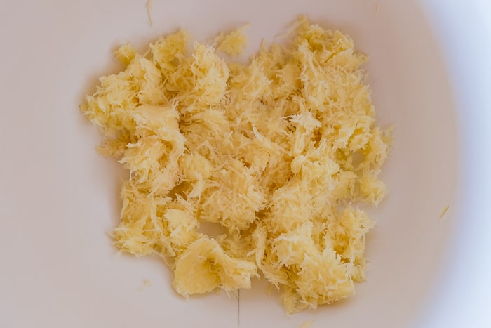 shredded potato in white mixing bowl