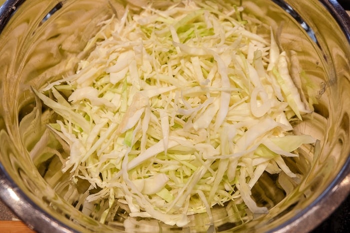 green cabbage cut into thin strips in a metallic bowl