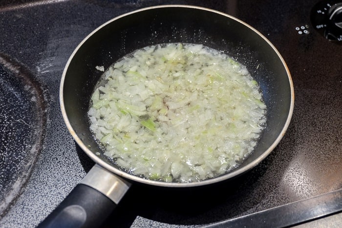 onions frying in a black frying pan on stovetop