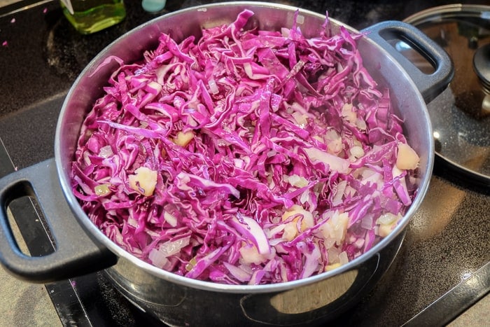 red cabbage and apples simmering in pot on stove