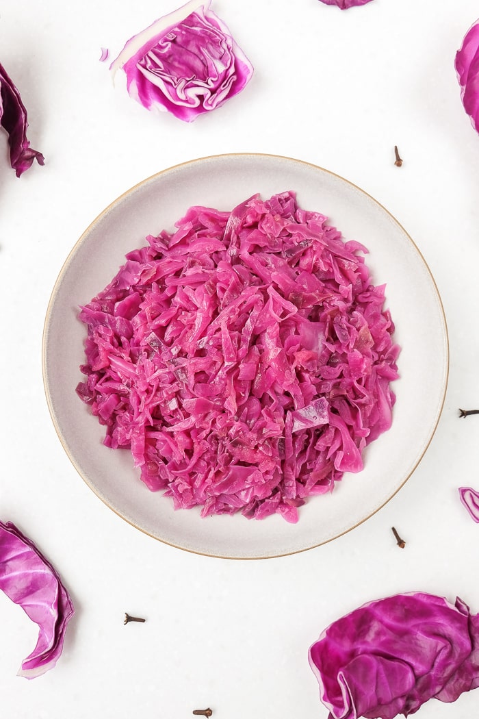 german red cabbage on white surface with cabbage leaves and cloves around