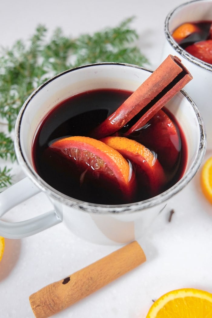 mug of red mulled wine with cinnamon stick and orange slices sticking out