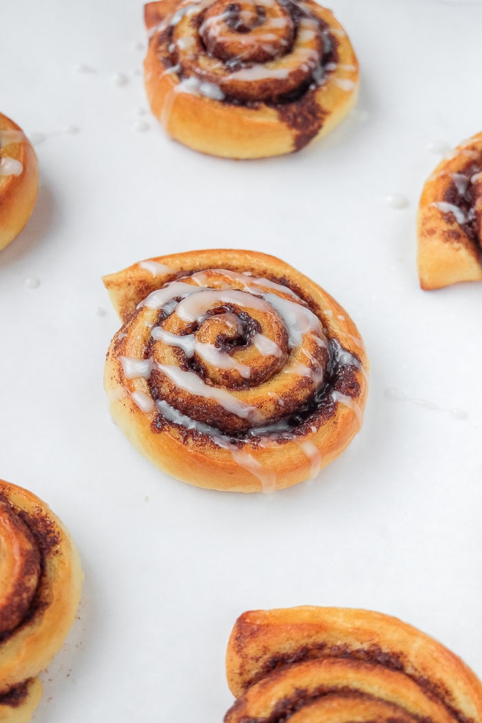 small cinnamon rolls with icing on white counter