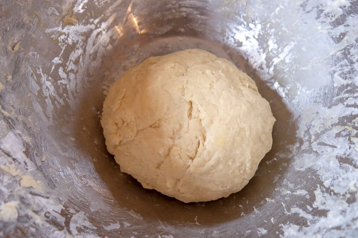 ball of homemade cinnamon bun dough in mixing bowl