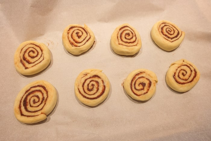 flattened cinnamon roll dough on white parchment paper