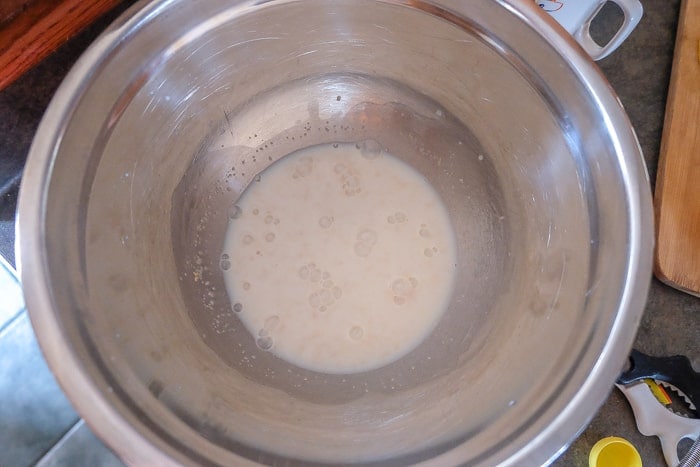 silver bowl of yeast and milk for cinnamon buns