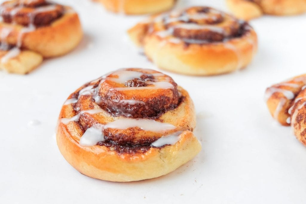 cinnamon buns with white icing on white counter top