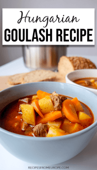 blue bowl of Hungarian goulash on white table with bread in background and text overlay saying Hungarian goulash recipe