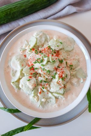 bowl of creamy cucumber salad with cucumber and napkin beside