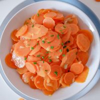 bowl of german carrot salad on white table with cloth above