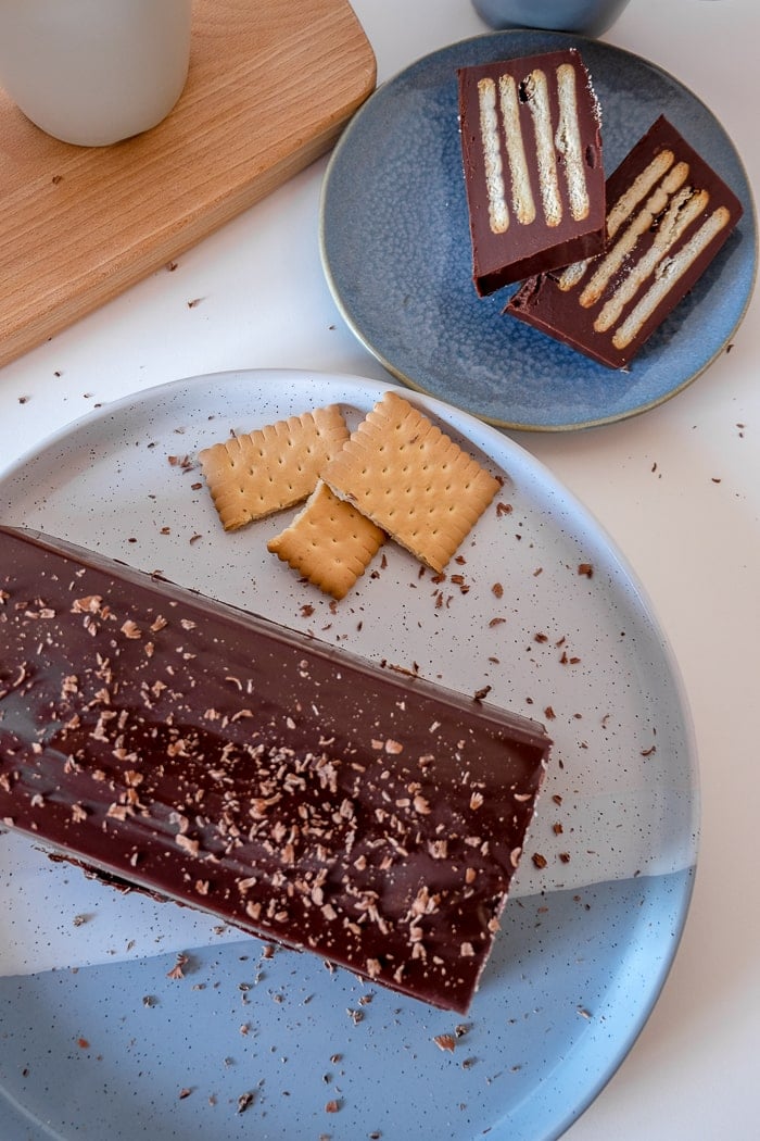 chocolate cake on blue plate with slices and cookies beside