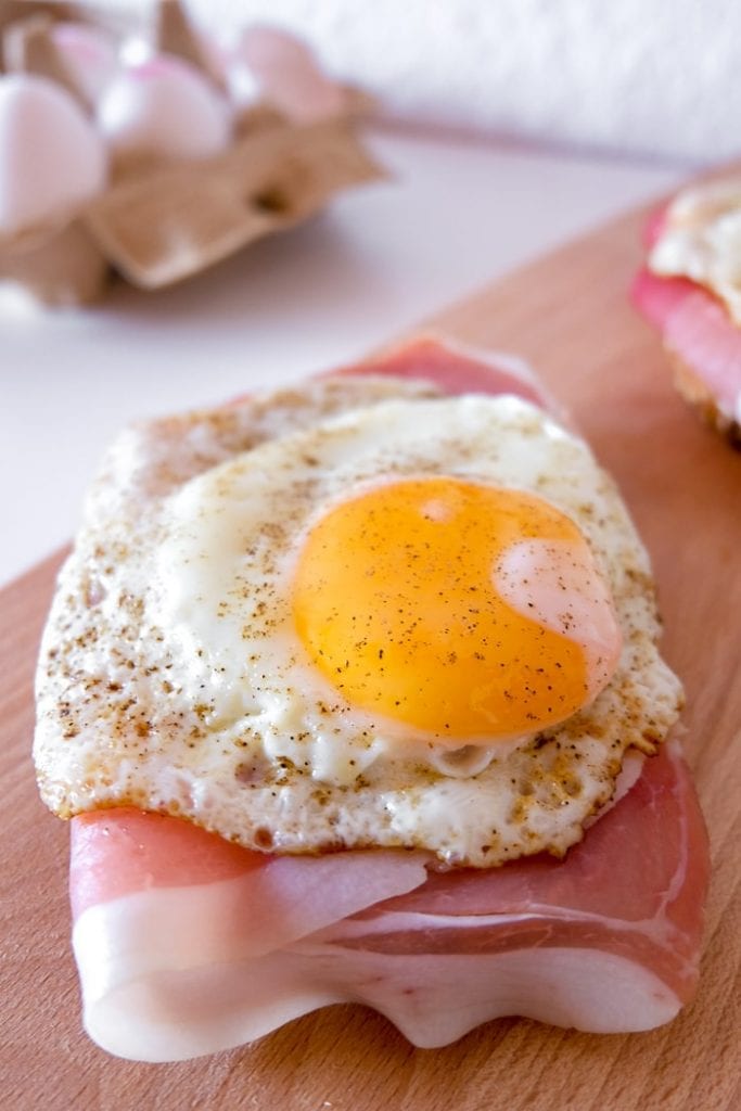 fried egg on ham and bread on wooden cutting board