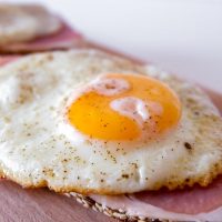 large fried egg yolk on ham and cutting board