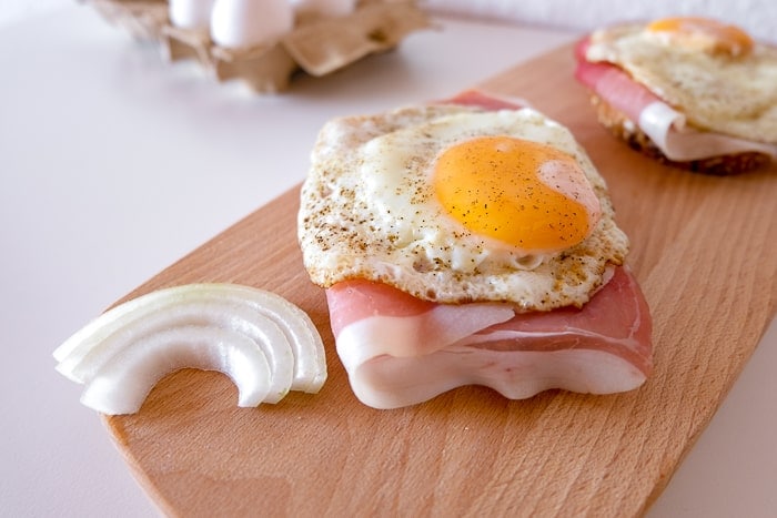 fried egg on bread with onion beside  on wooden cutting board
