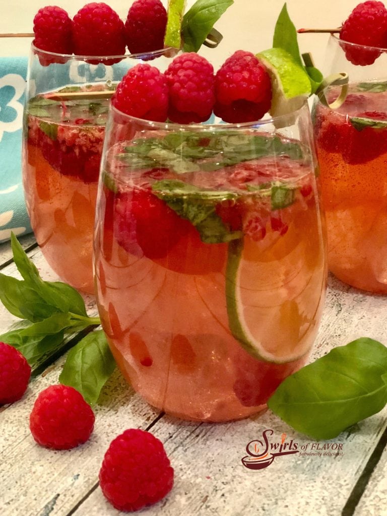 Red Sangria in glasses with raspberries, mint and lime as garnish.
