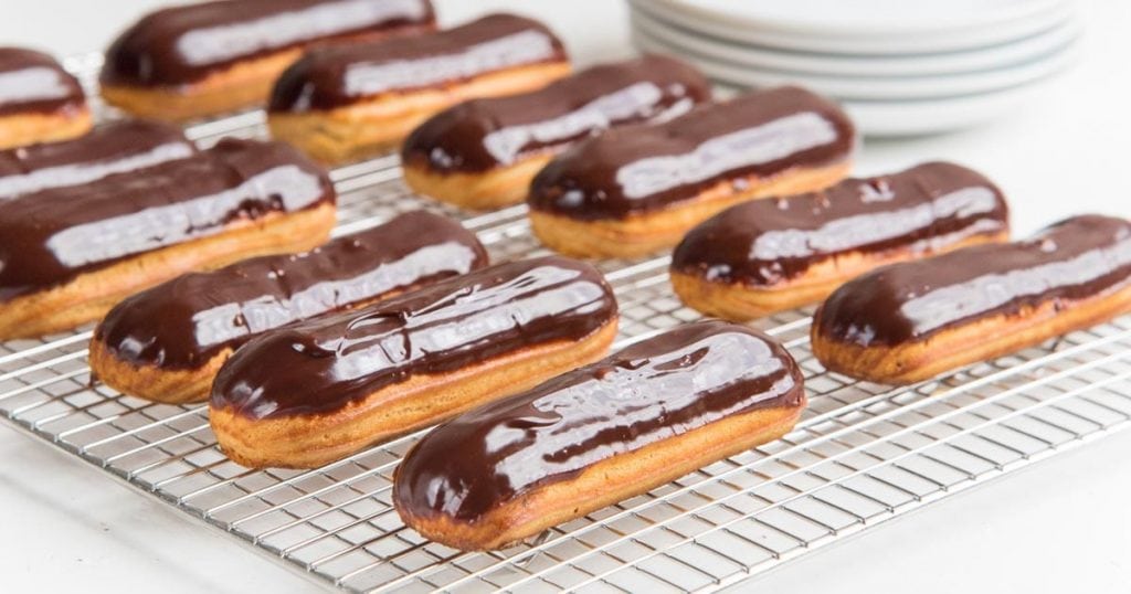 Chocolate eclairs on metal cooling tray.