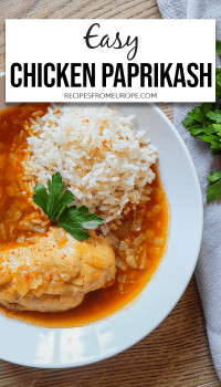 Plate of chicken, rice and red sauce on wood surface with text overlay saying easy chicken paprikash