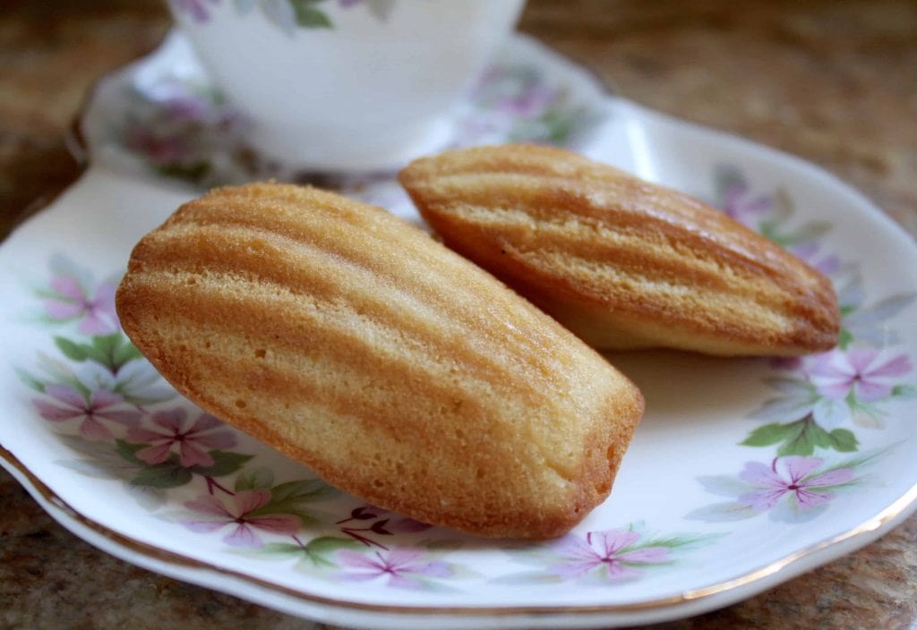 Madeleine pastry on white plate with flower design.