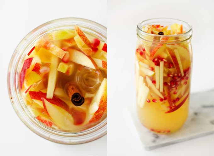 glass of yellow sangria with slices of apple and pomegranate seeds. 