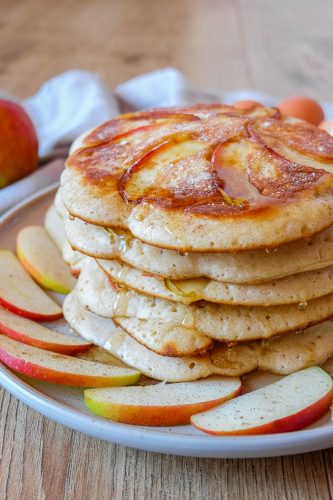 stack of german apple pancakes on plate with apple slices around