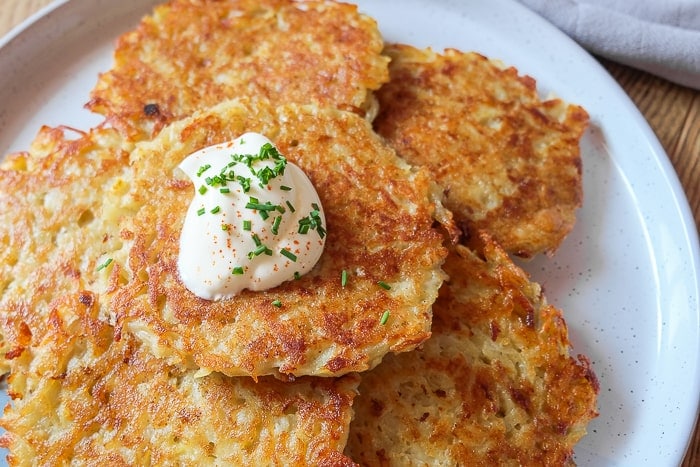 crispy potato pancakes on plate with scoop of quark and chives