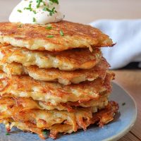 stack of golden brown german potato pancakes with cheese and chives on top
