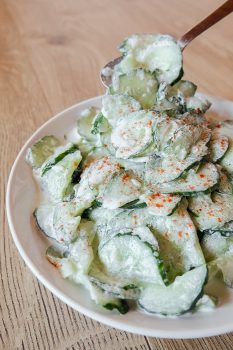 green hungarian cucumber salad in bowl with spoon scooping