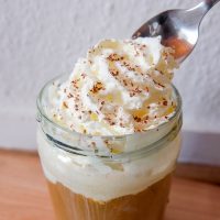 whipping cream with silver spoon dipping into ice cream coffee