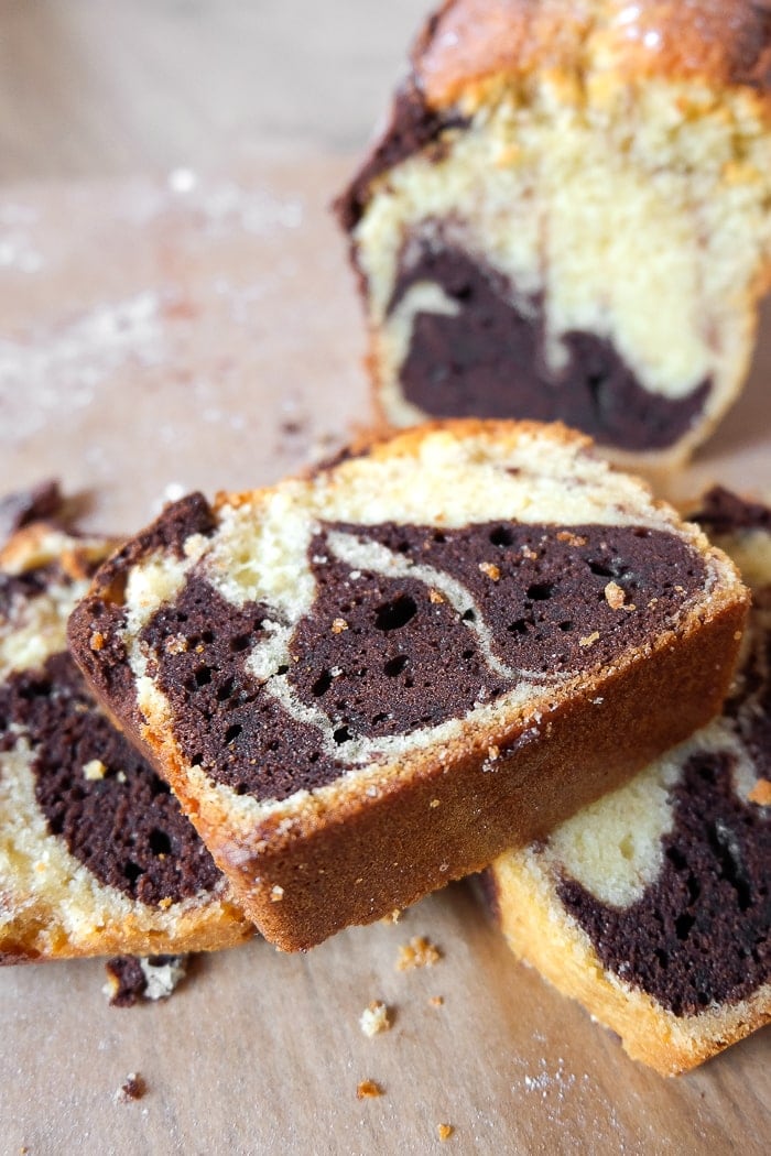 marble cake slices stacked on one another with loaf of cake behind on parchment paper