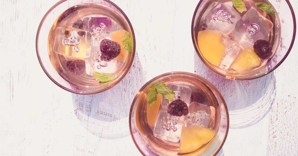 Photo from top of light sangria with berries and ice cubes in glasses. 