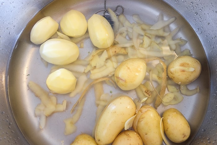 washed and peeled potatoes in water in metallic sink