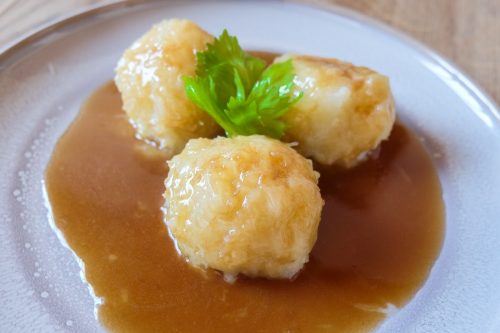 german potato dumplings with brown gravy on grey plate