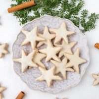 german cinnamon star cookies on plate with cinnamon sticks around