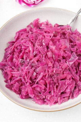 bowl of german red cabbage on white counter with silver spoon sticking out