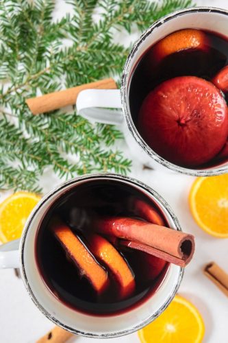 two mugs of german mulled wine with oranges and cinnamon around
