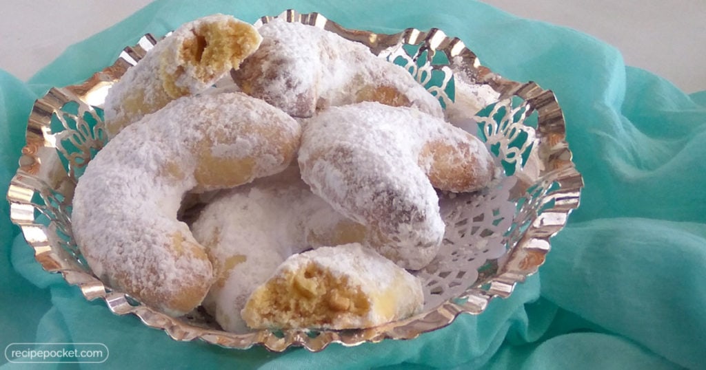 crescent shaped cookies with icing sugar on top in bowl. 