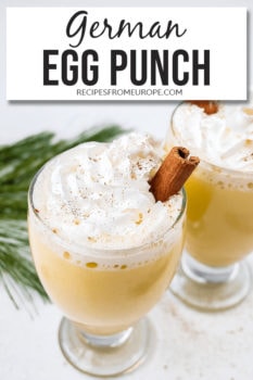 Photo of glasses with egg punch and whipped cream on top and cinnamon stick plus text overlay saying German egg punch