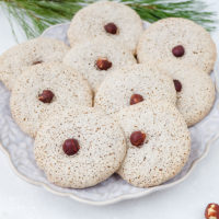 hazelnut cookies on festive plate with hazelnuts around on white counter