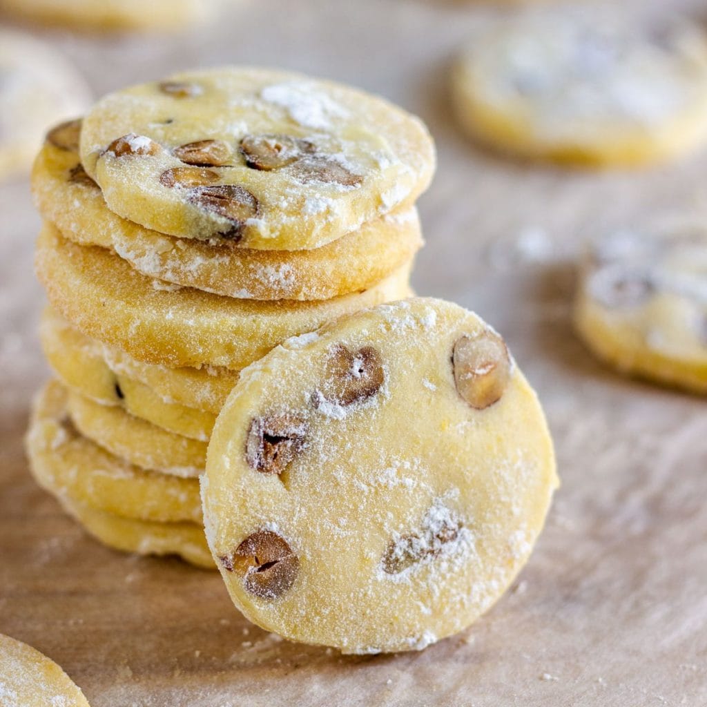 round cookies with hazelnuts in it and dusted in icing sugar stacked. 