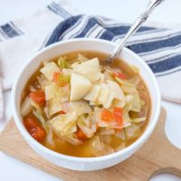 cabbage potato soup in bowl with spoon sticking out