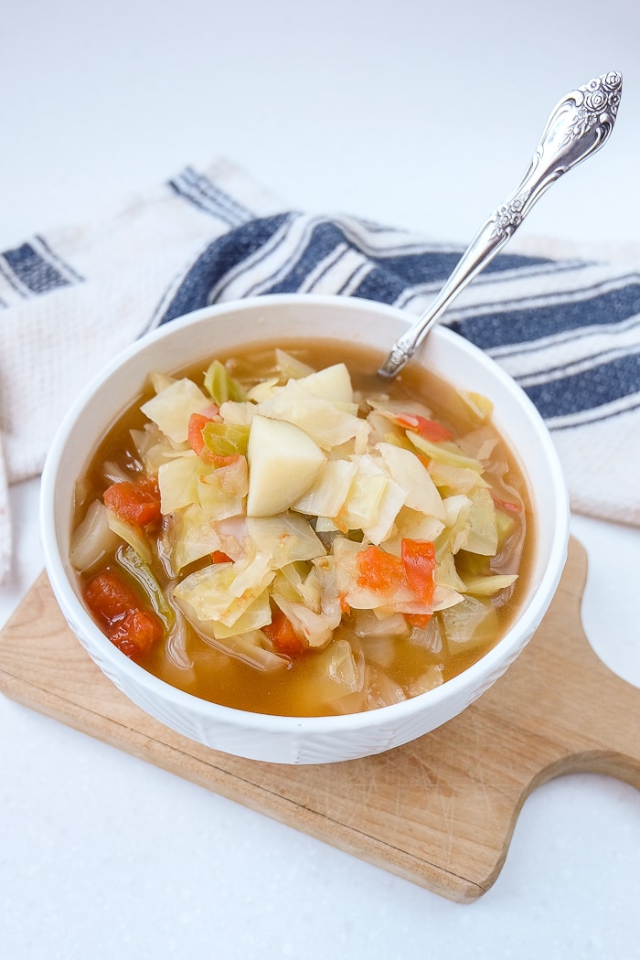 cabbage potato soup in bowl on wood with silver spoon sticking out