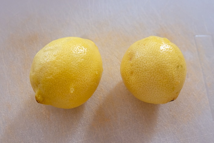 two lemons on white cutting board