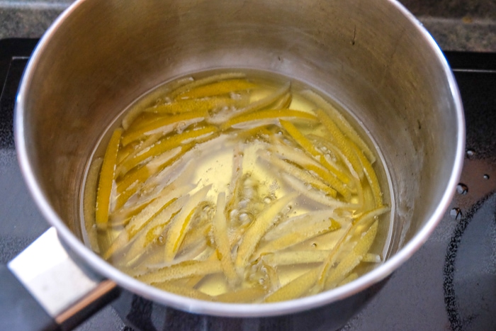 lemon peels in bubbling sugar in pot on stove