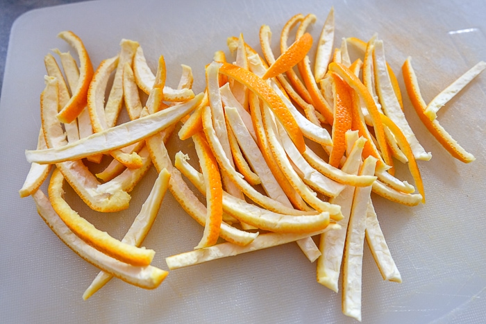 orange peels cut into thin strips on plastic cutting board